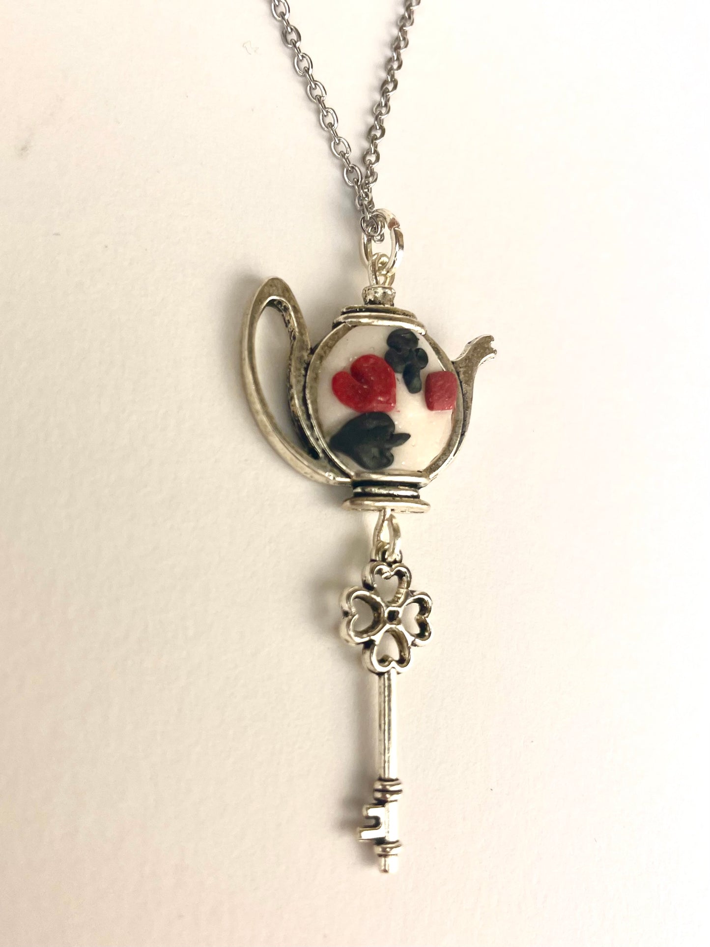 Collier Alice au Pays des Merveilles avec pendentif tasse et symbole de la Reine de Cœur.