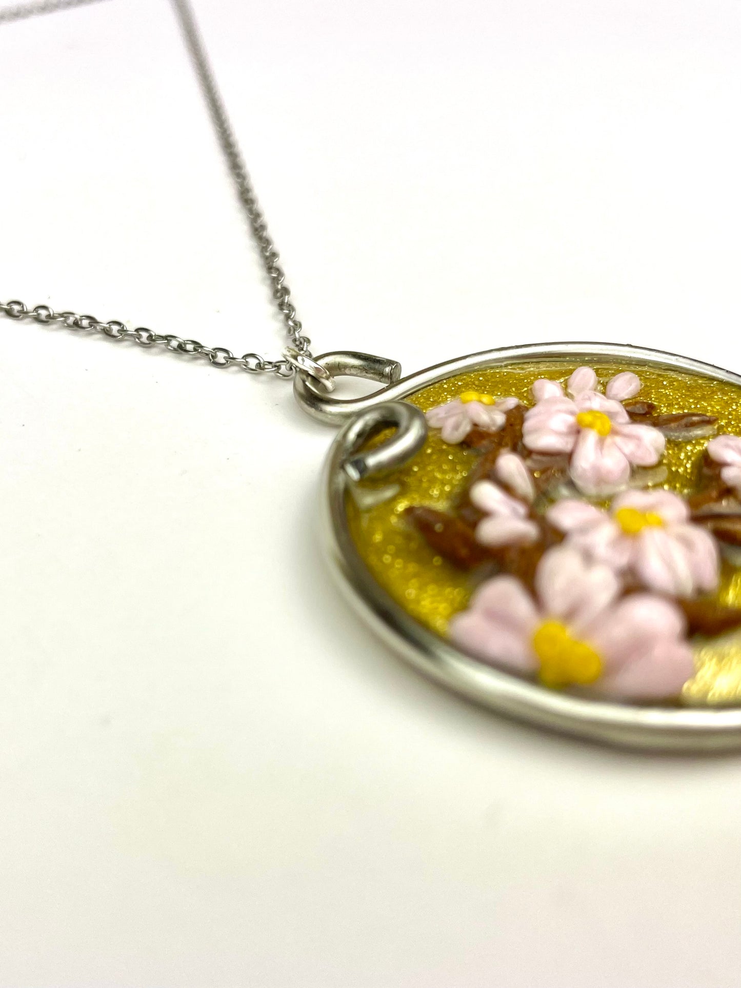 Pendentif rond doré décoré de fleurs de cerisiers en pâte polymère.