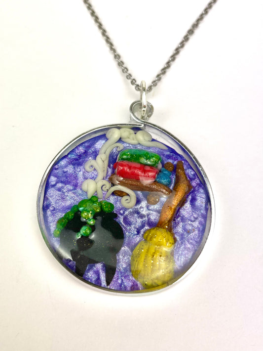 Médaillon artisanal avec chaudron, grimoire et balai sculptés